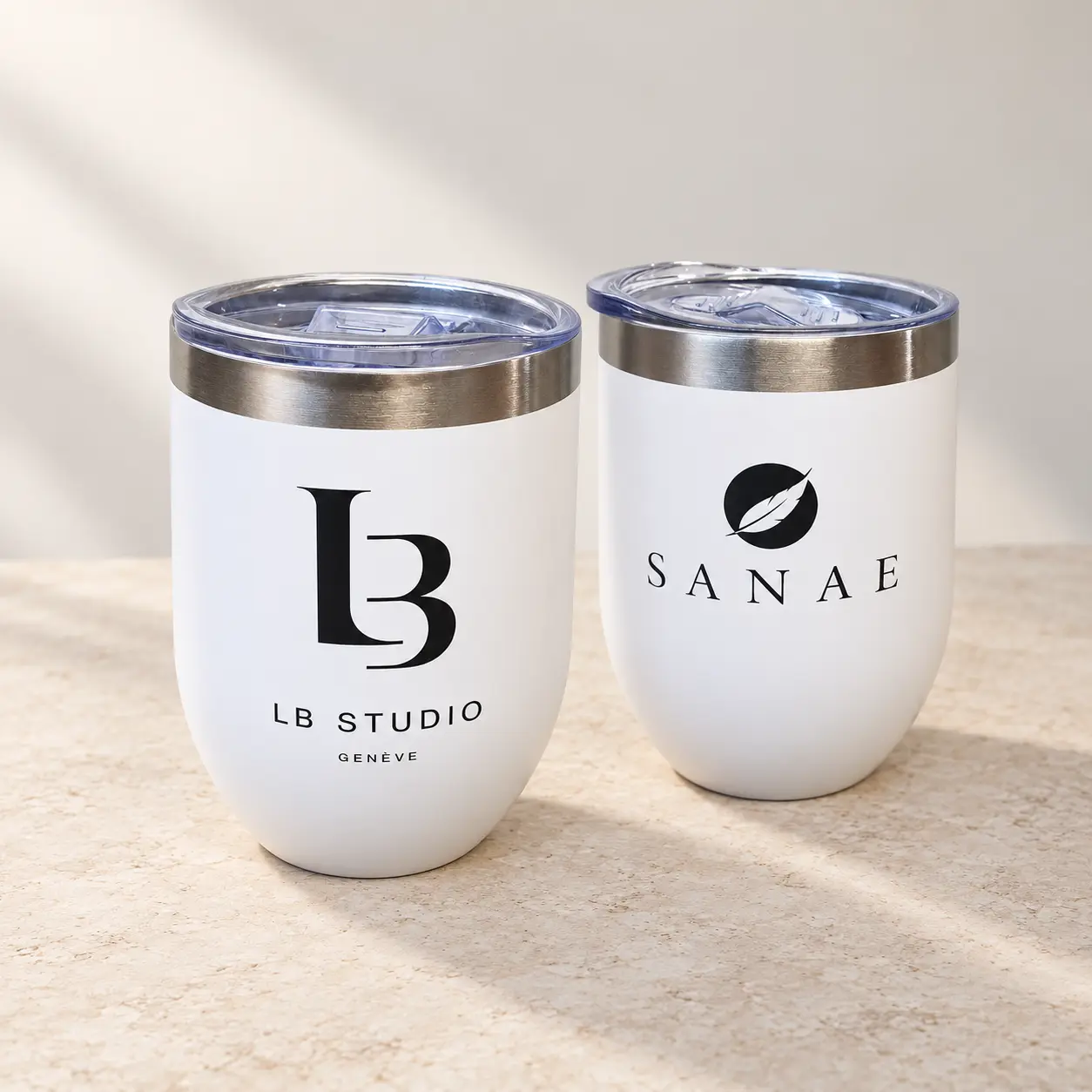 Deux gobelets isothermes blancs de 35 cl personnalisés avec les logos LB Studio Genève et SANAE